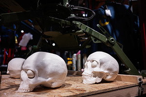 Realistic skull replicas on a wooden table in a dimly lit industrial setting, a Photo by AS photostudio