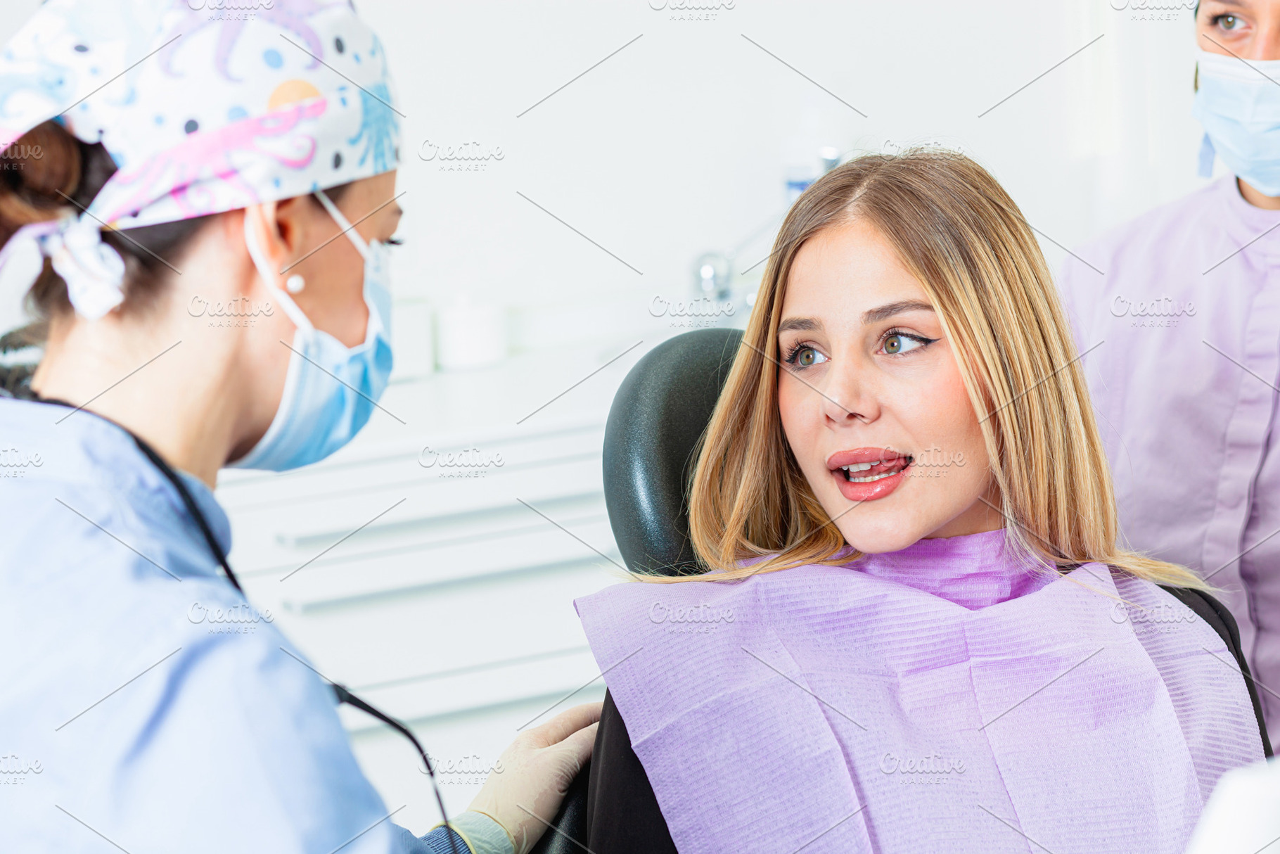 Dentist wearing surgical mask listening to patient explaining sy, a Health & Medical Photo by Antonio Gravante Market