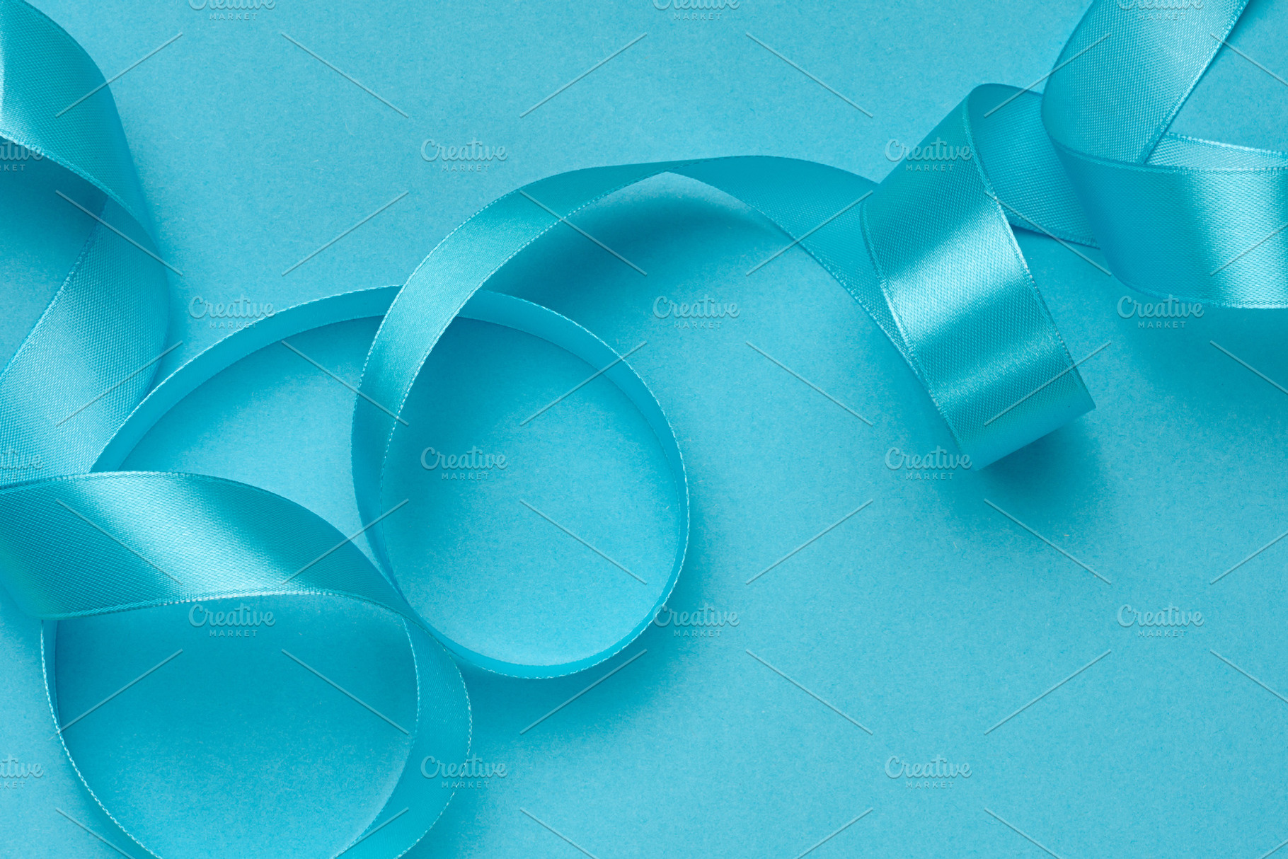 A satin blue ribbon folded in graceful waves and curls on a soli, a Holiday Photo by ndanko