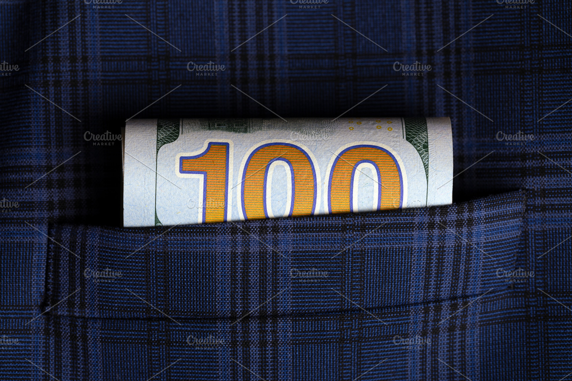 Rolled one hundred dollar bill tucked into a blue plaid suit pocket, symbolizin, a Business Photo by Ales Munt