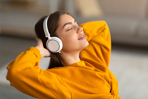 Calm young Caucasian woman listening to music in wireless headphones, relaxing, a Photo by Prostock-Studio
