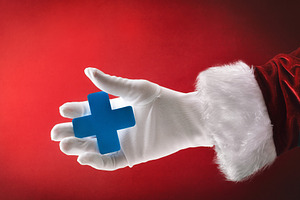 Santa Claus hand holding health cross on snowing blue background, a Holiday Photo by Davizro's Market