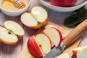 Sliced red apples and honey on wooden table, a Food & Drink Photo by Olena Rudo