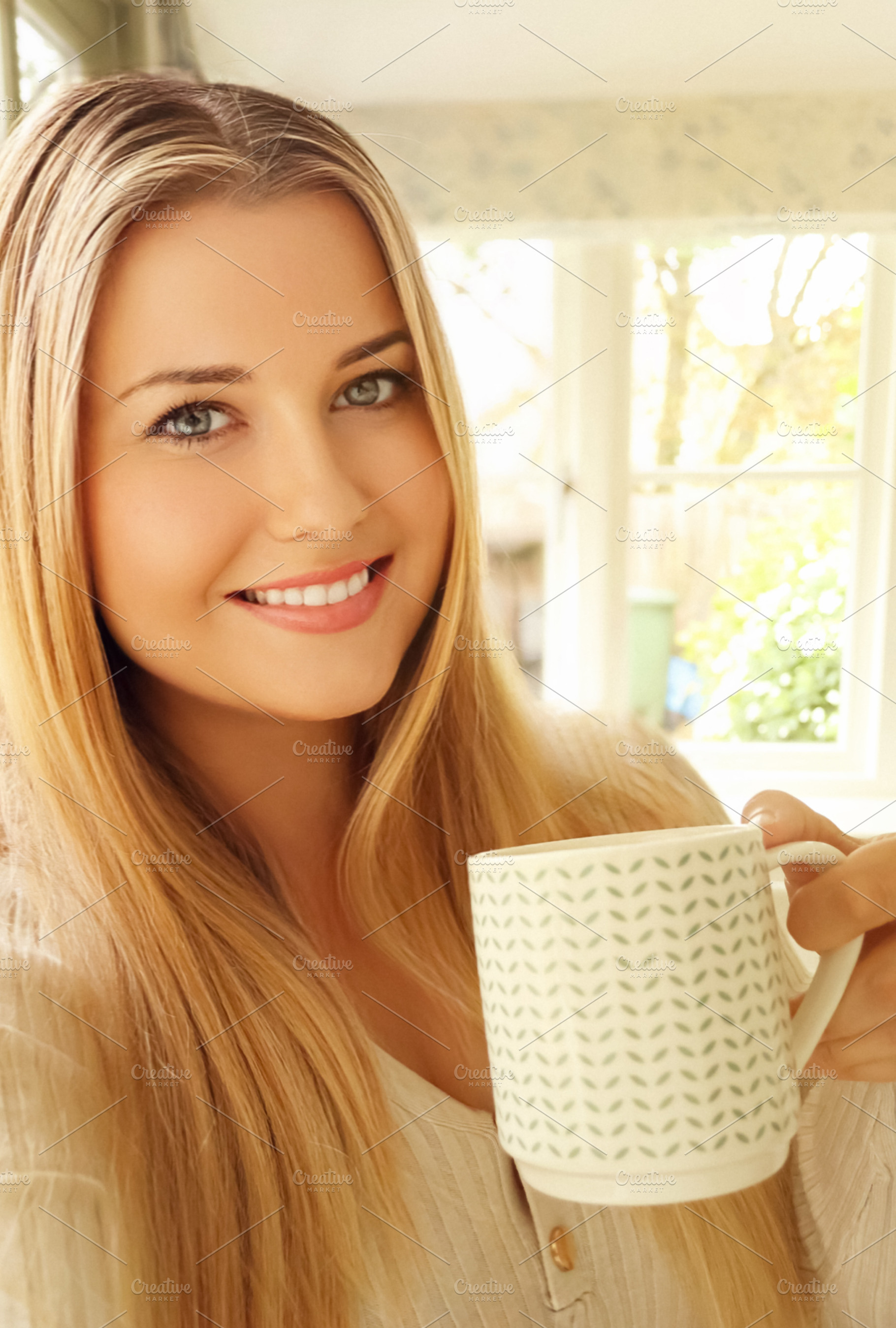 Blonde woman having a coffee, milk or tea in a mug, smiling, sta, a Person Photo by Studio ANNA