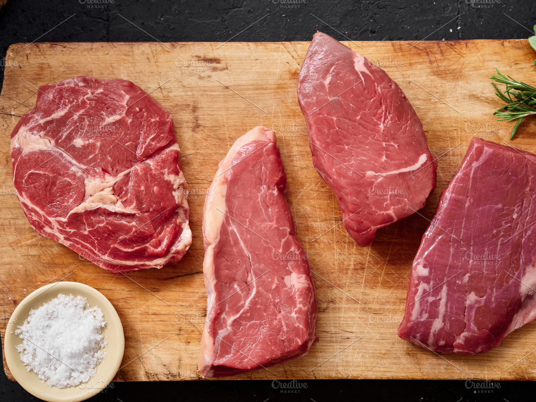 Raw rib-eye, roast beef, flank and rump steak displayed on wooden cutting board, a Food & Drink Photo by Asya Nurullina