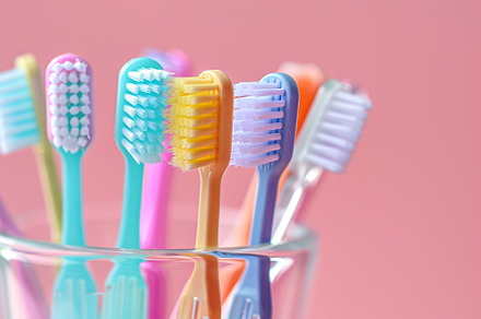 New toothbrushes in glass on pink background, a Health & Medical Photo by AlyaAnd