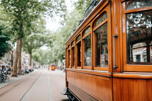 Vintage wooden tram on a tree-lined street, a Transportation Photo by AlyaAnd
