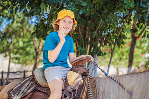 Smiling child enjoys a horse ride, a Person Photo by Elizaveta Galitskaya