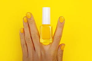 Hand with manicured yellow nails and matching nail polish bottle, a Beauty & Fashion Photo by Ales Munt