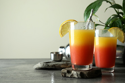Tequila Sunrise cocktails on gray textured table, a Food & Drink Photo by AtlasStudio PRO