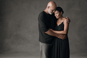 Couple embracing in a warm moment against a muted background in a studio settin, a Photo by AlyaAnd