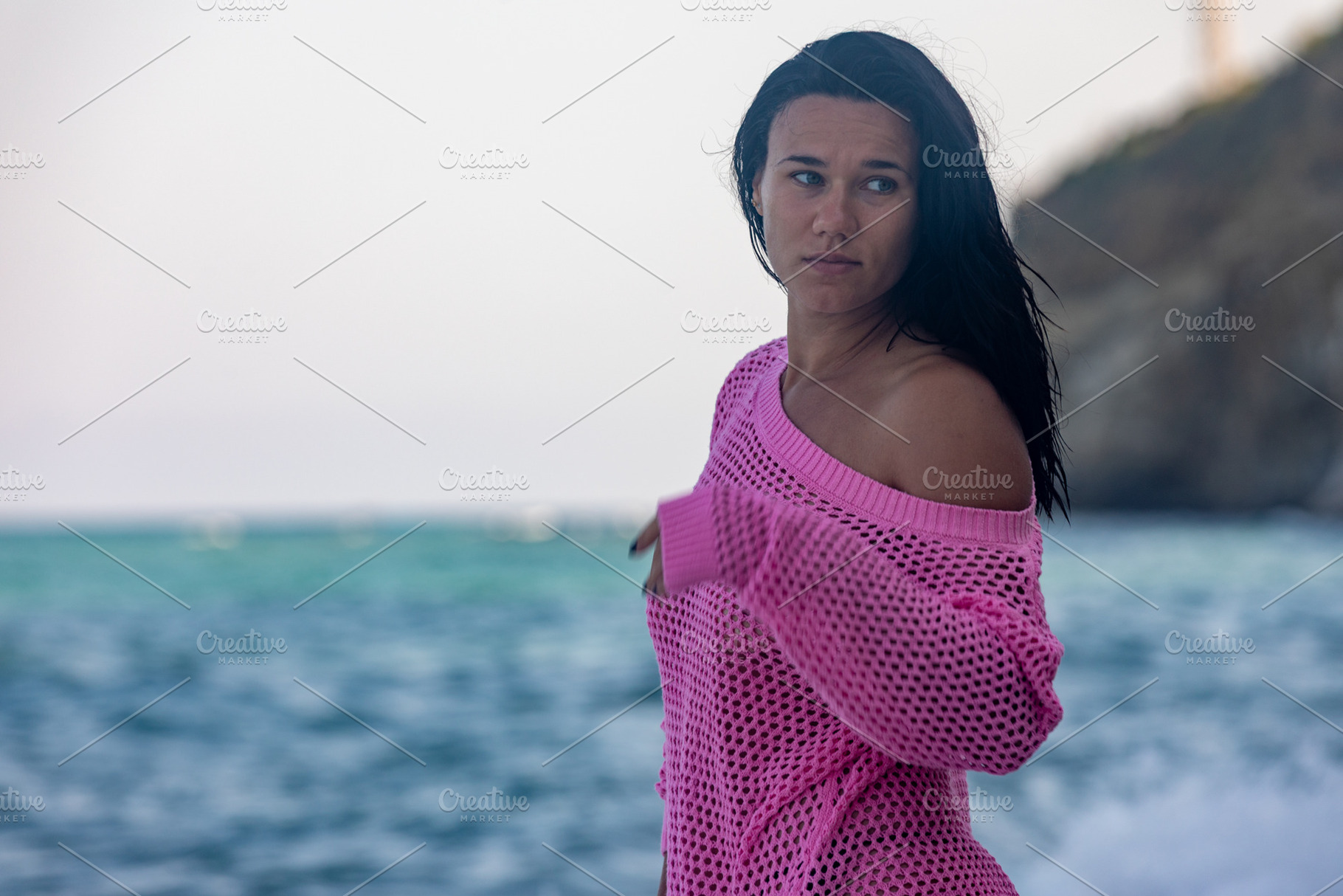 Young woman in a bright pink sweater standing by the ocean, gazing away, with a, a Person Photo by Ales Munt