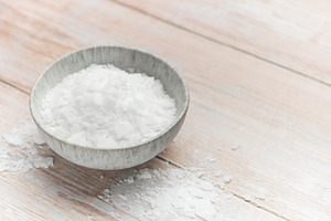 Magnesium chloride flakes in a bowl on rustic wooden table, a Health & Medical Photo by Olena Rudo