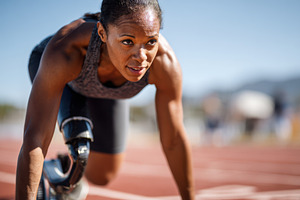 Determined athlete with prosthetic leg on track, a Sports & Recreation Photo by AlyaAnd