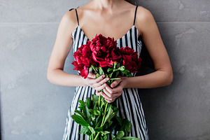 Felame in striped dress holding a red peonies