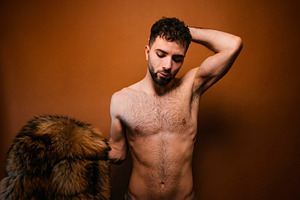 Bearded man posing shirtless with fur coat, a Photo by karrastock