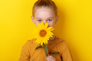Young girl with blue eyes holding a sunflower, matching yellow b, a Person Photo by Ales Munt
