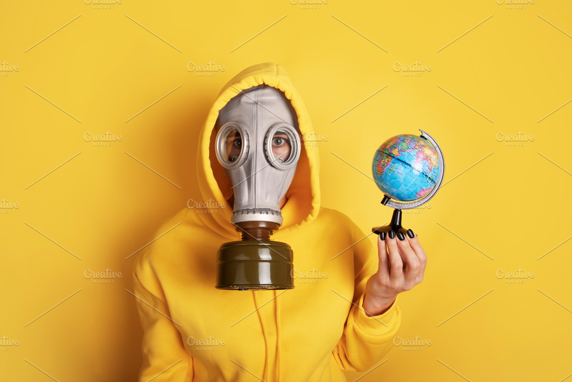 Individual wearing a gas mask and yellow hoodie holds a small gl, a Person Photo by Ales Munt
