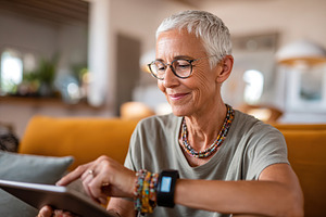 Woman engaging with health-monitoring device while relaxing at home in modern l, a Photo by AlyaAnd