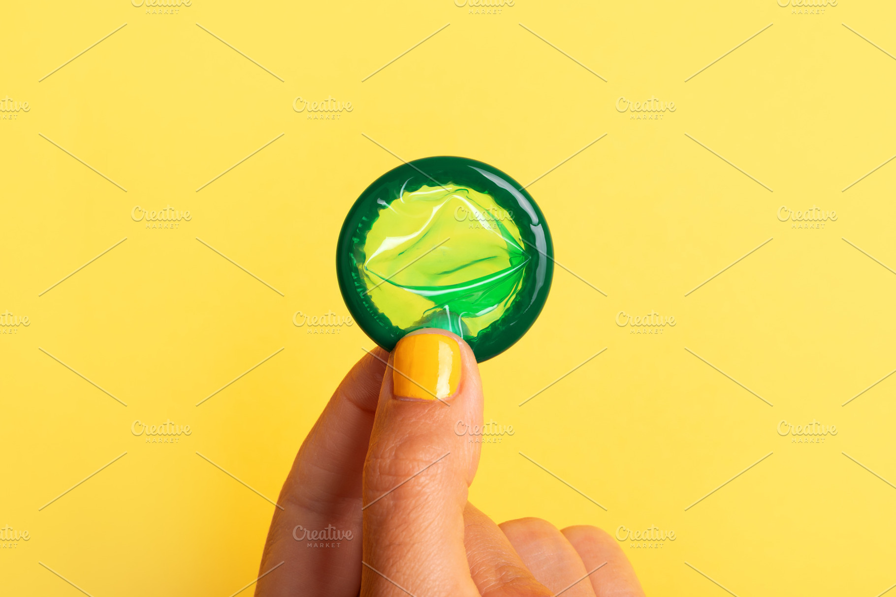 Close-up of a green rolled condom balanced on a finger with yel, a Health & Medical Photo by Ales Munt