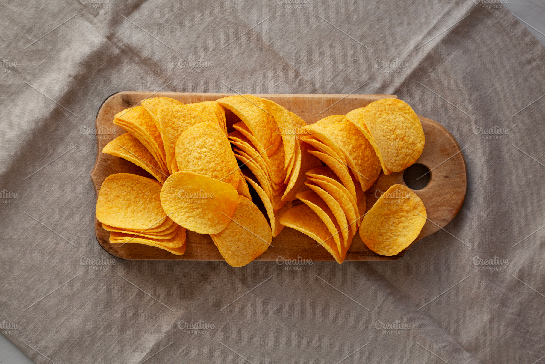 Bacon flavoured potato chips on a wooden board, top view., a Food & Drink Photo by LiudmylaChuhunova