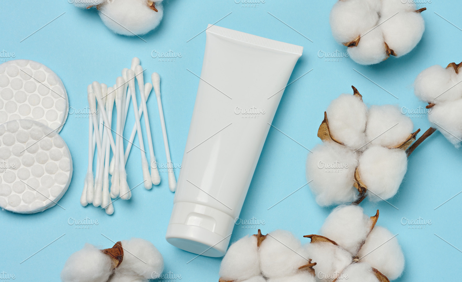 White tube, cotton pads and cotton flowers on a blue background,, a Beauty & Fashion Photo by ndanko