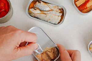 man opening a can of canned frigate tuna fillets, a Photo by Nito