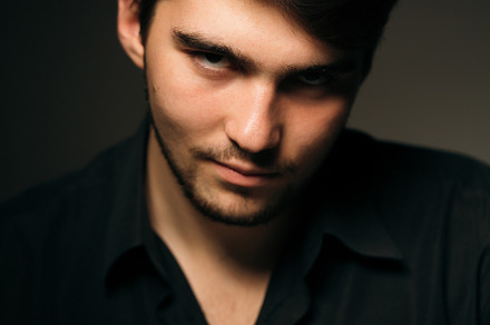 Young brunette guy on a dark background containing fashion, male, and guy