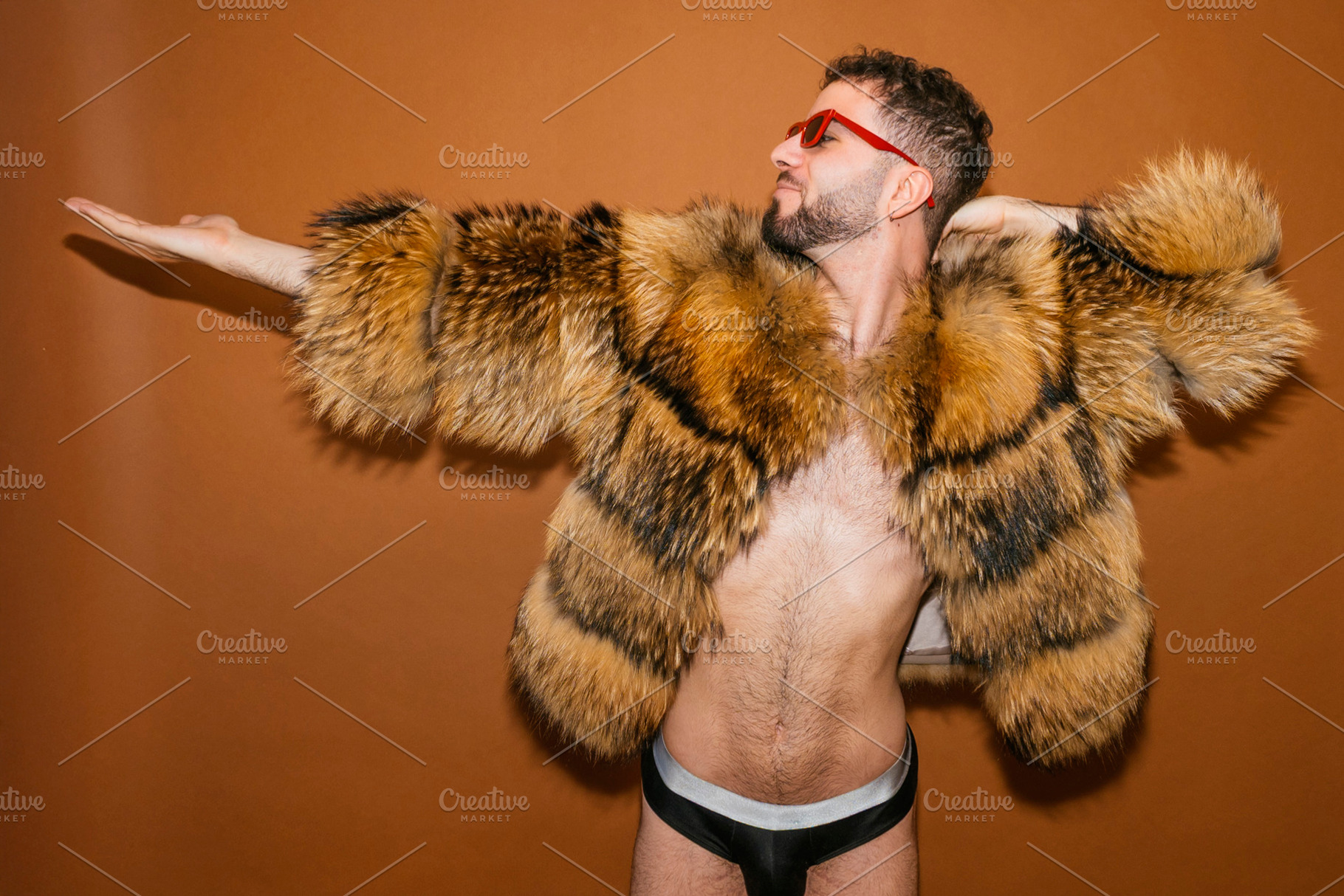 Young adult man posing in fur coat for pride, a Photo by karrastock