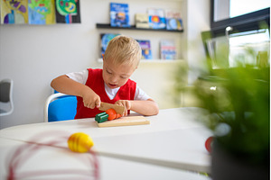 Boy with down syndrome cutting toy, a School & Education Photo by HalfPoint