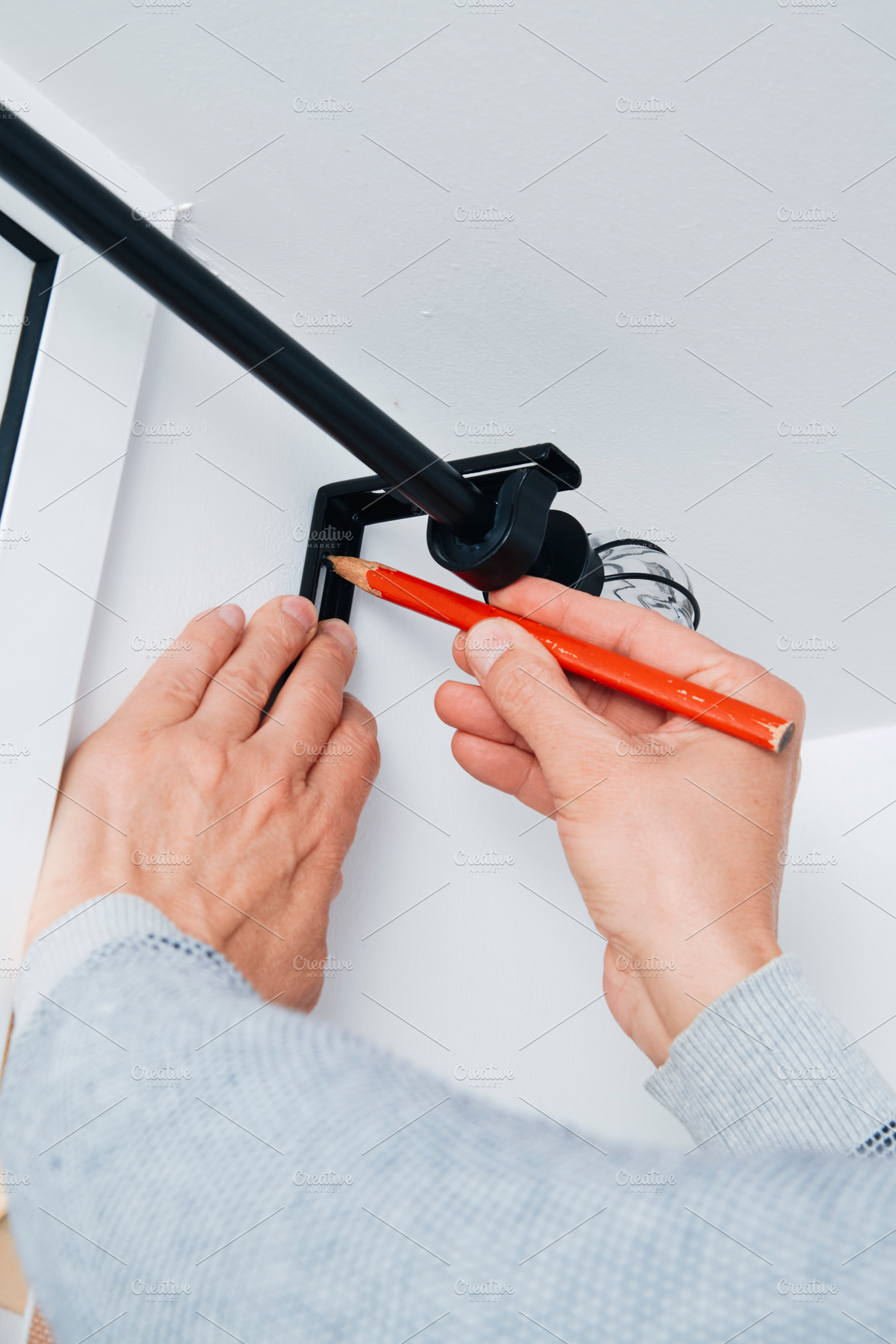 a man marking a point on the wall with a pencil, a Photo by Nito