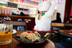 Closeup of sushi and drink on table in vibrant restaurant interior setting, a Photo by AS photostudio