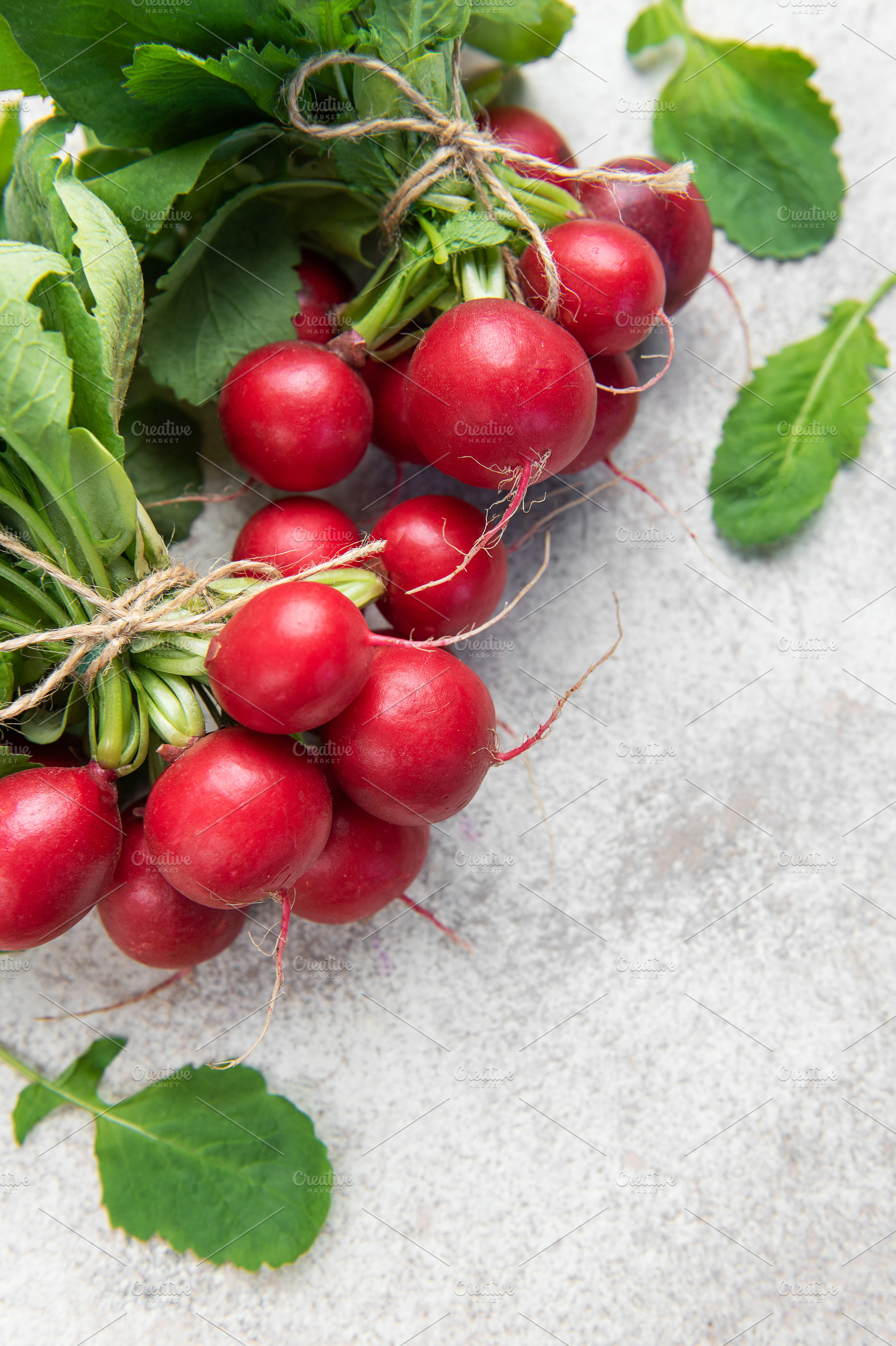 Fresh radishes bunch with green leaves on light background, a Food & Drink Photo by Olena Rudo