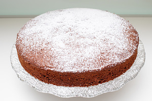 Round caprese cake with icing sugar on glass cake stand, a Food & Drink Photo by Antonio Gravante Market