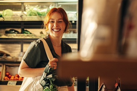 Cheerful young woman grocery shopping in a supermarket, a Person Photo by Jacob Lund