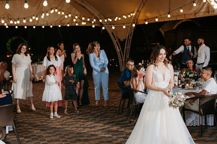 bride in a white dress throws a wedding bouquet