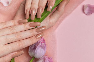 Woman hand with stylish nude manicure holding purple tulips on p, a Beauty & Fashion Photo by Olena Rudo