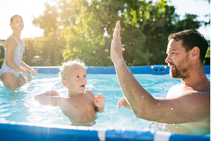 Father playing in swimming pool with, a Person Photo by HalfPoint