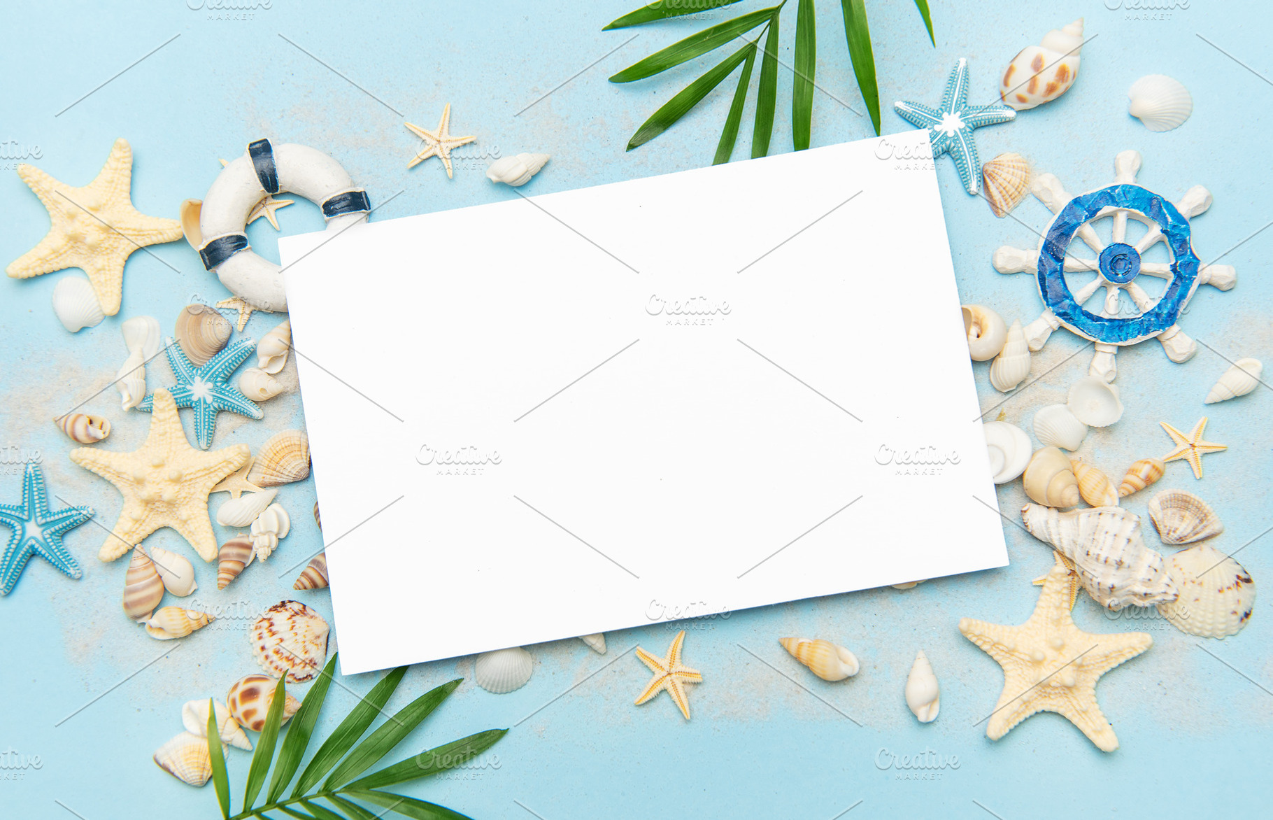Blank card surrounded by seashells and starfish on sandy beach, a Holiday Photo by Olena Rudo
