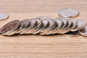 A row of Ukrainian metal coins lies on a wooden table., a Business Photo by ndanko