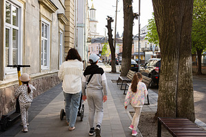 A family strolling on a sunny path with charming urban scenery and trees, a Person Photo by AS photostudio