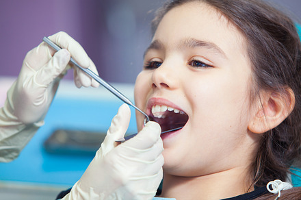 Closeup of pretty little girl opening his mouth wide during treating her
