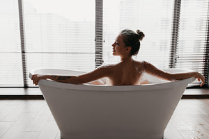 Back view of young lady taking foamy bath, looking aside at free space at home, a Photo by Prostock-Studio