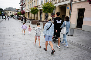 Family walking through a city street in Rzeszow, Poland on a cloudy day, a Photo by AS photostudio