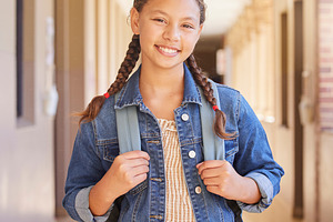 School, Backpack and portrait of girl student with education to learn, study and have knowledge. Happy, smile and child standing in the hallway or aisle with her bag for class in a high school campus, a Photo by Peopleimages.com