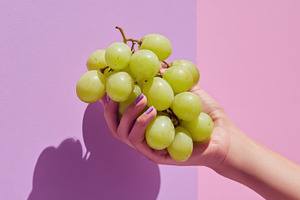 Green grapes held against two colors, a Photo by Beautiful things