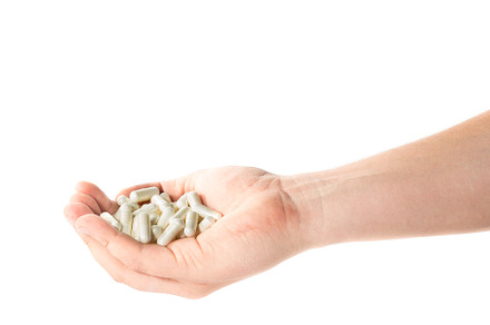 Image of a hand full of medical capsules on a white background