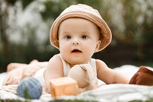 Beautiful happy baby in hat lying on blanket and playing with to, a Person Photo by Sonjachni