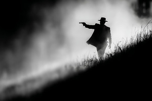 Shadowy silhouette of a figure holding a firearm in a misty terrain, a Photo by AS photostudio