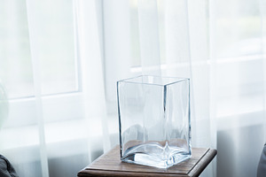 Empty glass vase on wooden stool near window in minimalist inter, an Industrial Photo by MDBildes